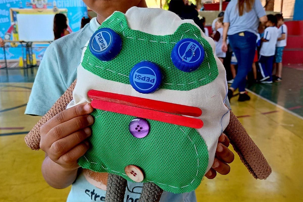 Crianças segurando bonecos squeezy criados com material reciclado em Alfenas